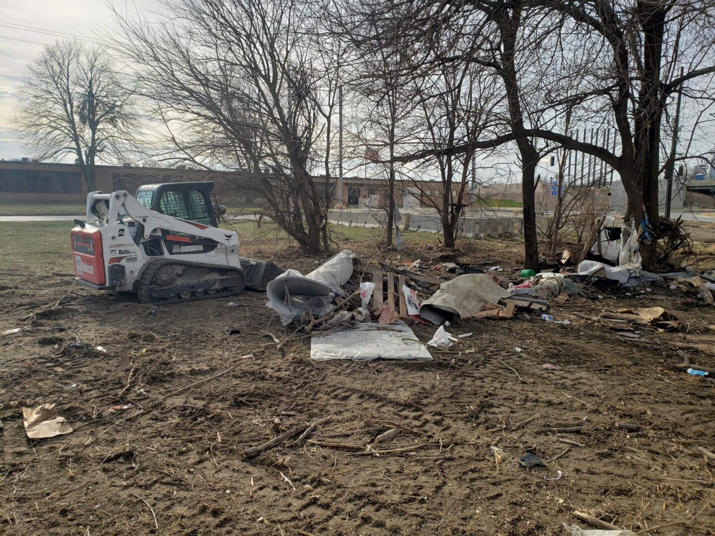 A white and black truck some trees bushes and trash