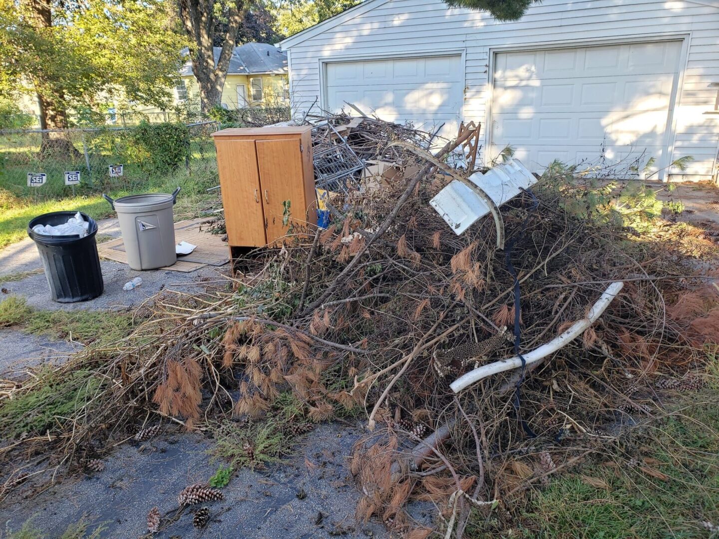 A pile of leaves and branches in front of a house.