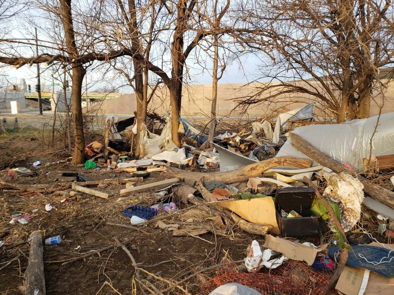 A bunch of trash thrown outside in front of trees